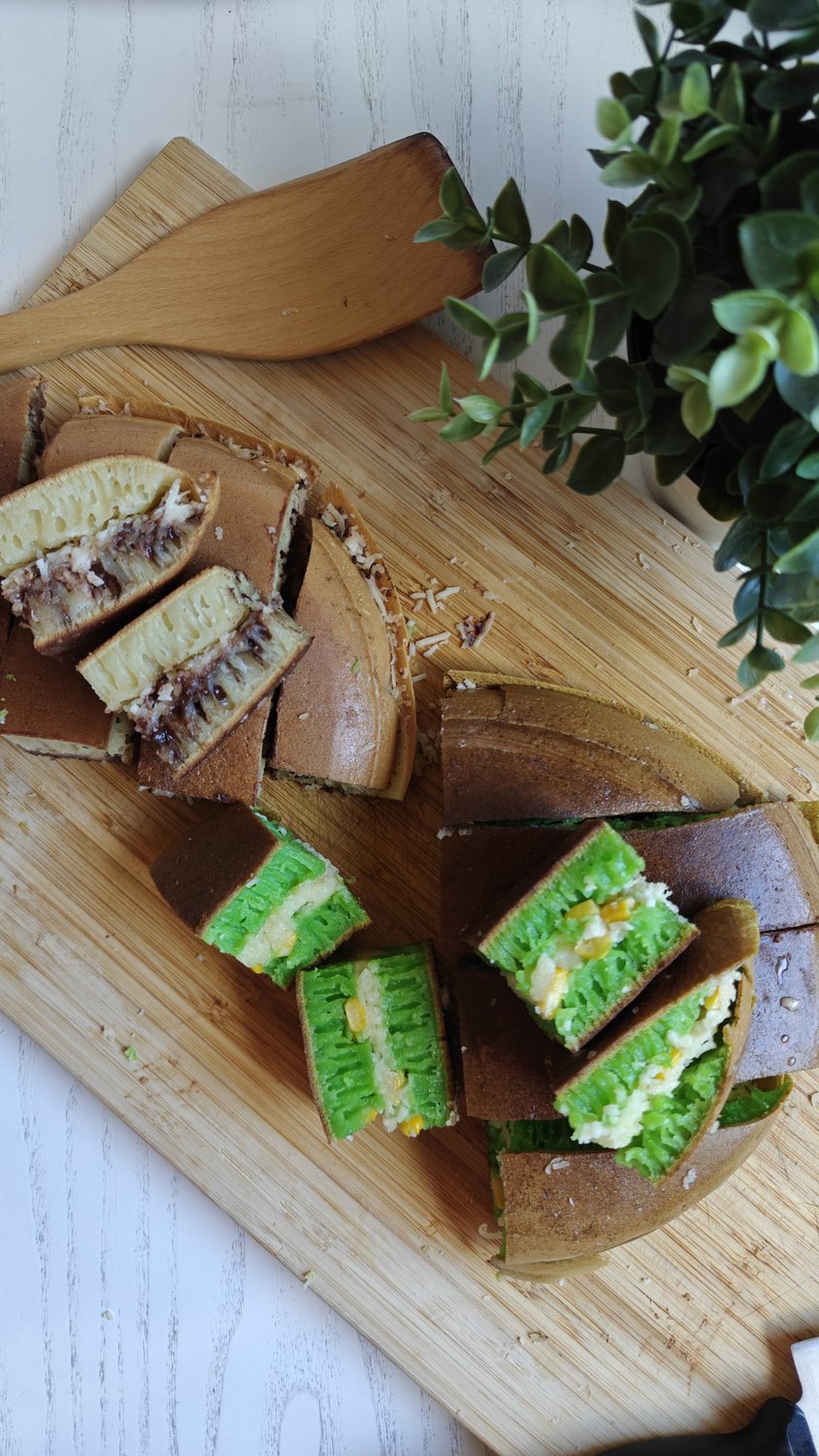 Two sliced martabak manis on a board, one chocolate-coconut and one green pandan